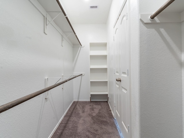 walk in closet featuring dark carpet