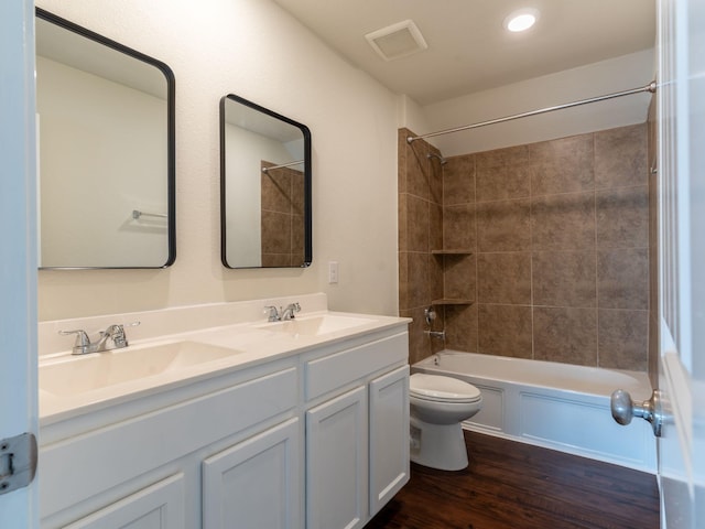 full bathroom featuring vanity, tiled shower / bath combo, wood-type flooring, and toilet