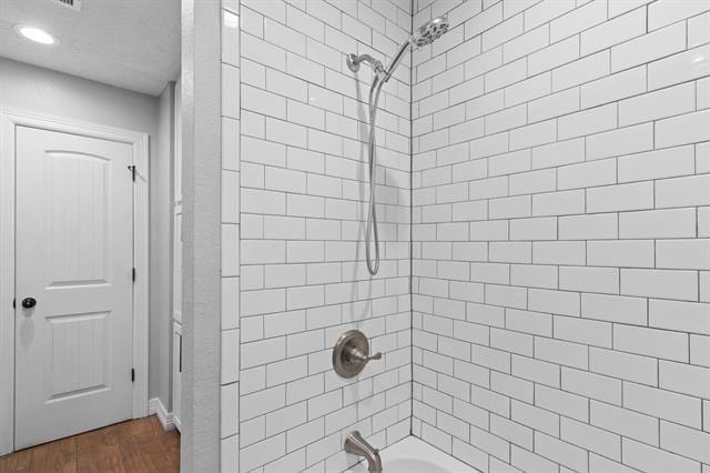 bathroom with hardwood / wood-style flooring and tiled shower / bath