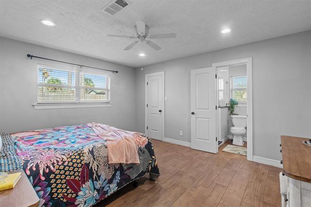 bedroom featuring hardwood / wood-style floors, ensuite bath, a textured ceiling, and ceiling fan