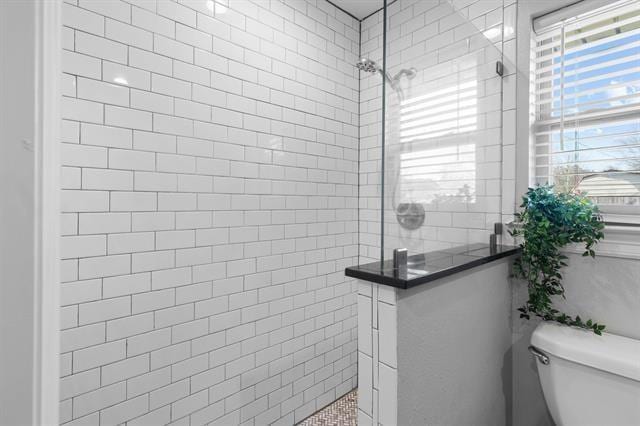 bathroom featuring tiled shower and toilet