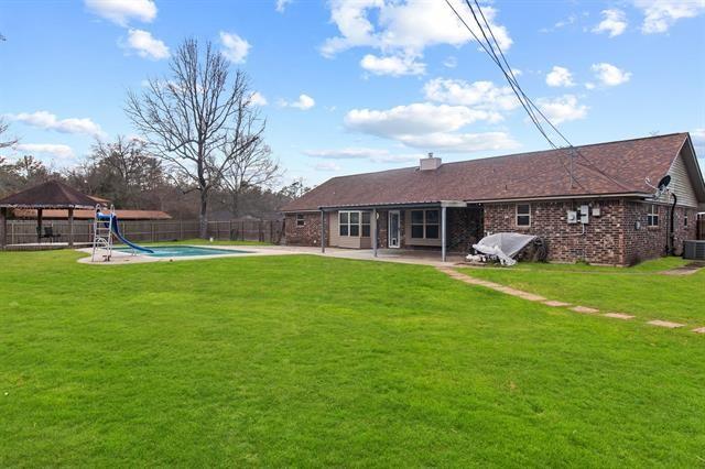 back of property featuring a gazebo, a patio, a fenced in pool, and a lawn