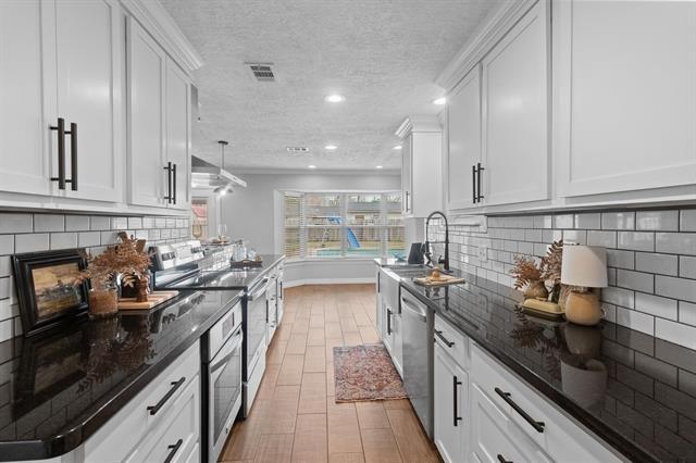 kitchen with dark stone counters, white cabinets, and appliances with stainless steel finishes