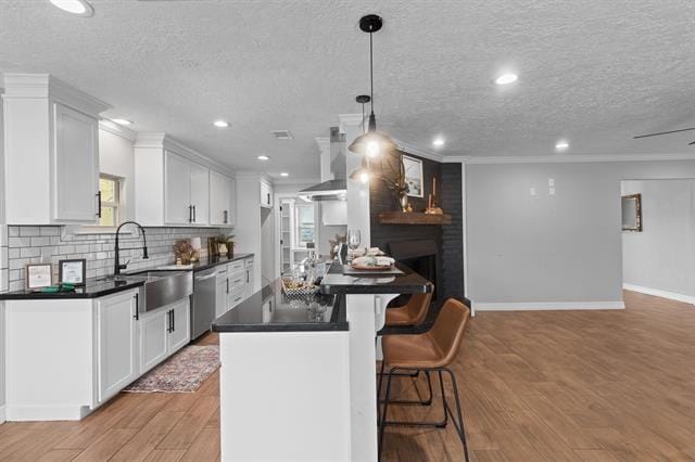 kitchen featuring sink, extractor fan, decorative light fixtures, stainless steel dishwasher, and white cabinets