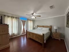 bedroom with ornamental molding, dark hardwood / wood-style floors, and ceiling fan