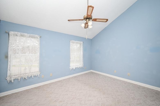 carpeted spare room featuring ceiling fan, vaulted ceiling, and baseboards