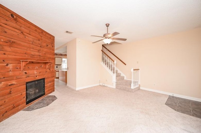 unfurnished living room featuring stairs, light carpet, a brick fireplace, baseboards, and visible vents