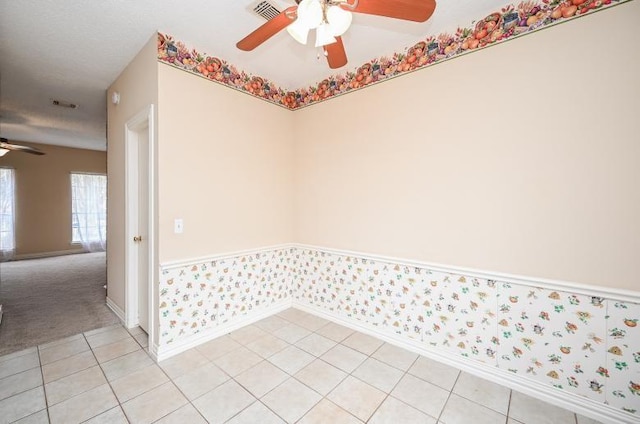 carpeted empty room with baseboards, visible vents, a ceiling fan, tile patterned flooring, and wallpapered walls