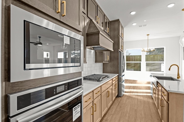 kitchen featuring a sink, premium range hood, stainless steel appliances, light countertops, and recessed lighting