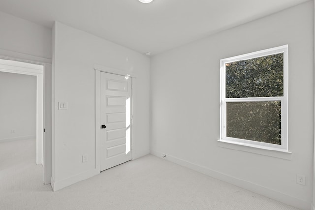 unfurnished room with light colored carpet and baseboards