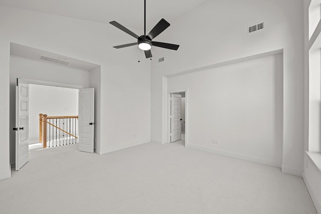 carpeted spare room featuring ceiling fan, a towering ceiling, and baseboards
