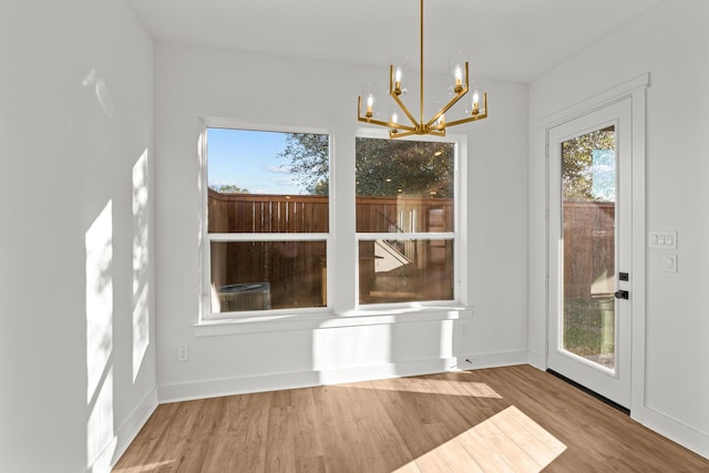 unfurnished dining area featuring a chandelier, wood finished floors, and baseboards