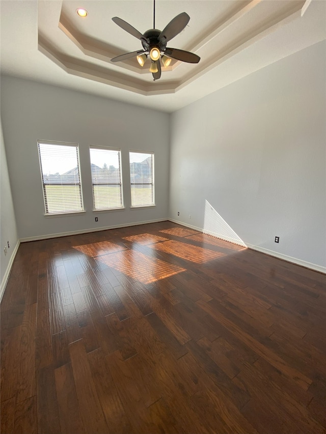 spare room featuring ceiling fan, a tray ceiling, and dark hardwood / wood-style flooring