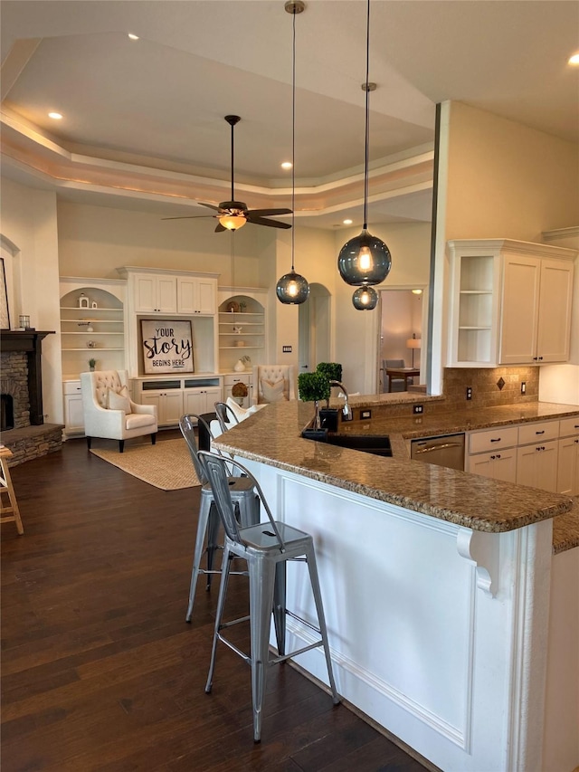 kitchen with a raised ceiling, hanging light fixtures, and a breakfast bar area