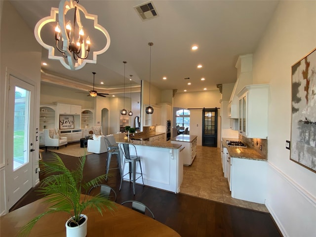 kitchen featuring pendant lighting, dark stone countertops, a kitchen breakfast bar, white cabinets, and kitchen peninsula