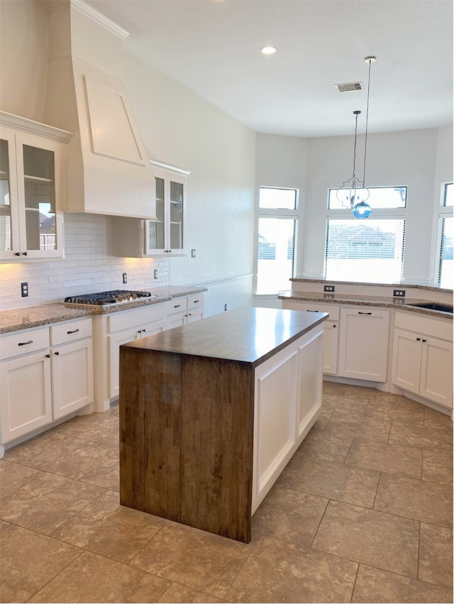 kitchen with white cabinetry, decorative light fixtures, stainless steel gas cooktop, and a center island