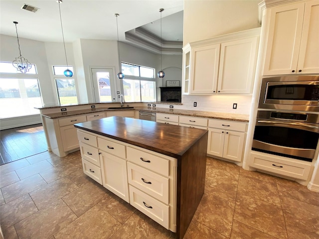 kitchen featuring sink, appliances with stainless steel finishes, a healthy amount of sunlight, decorative light fixtures, and kitchen peninsula