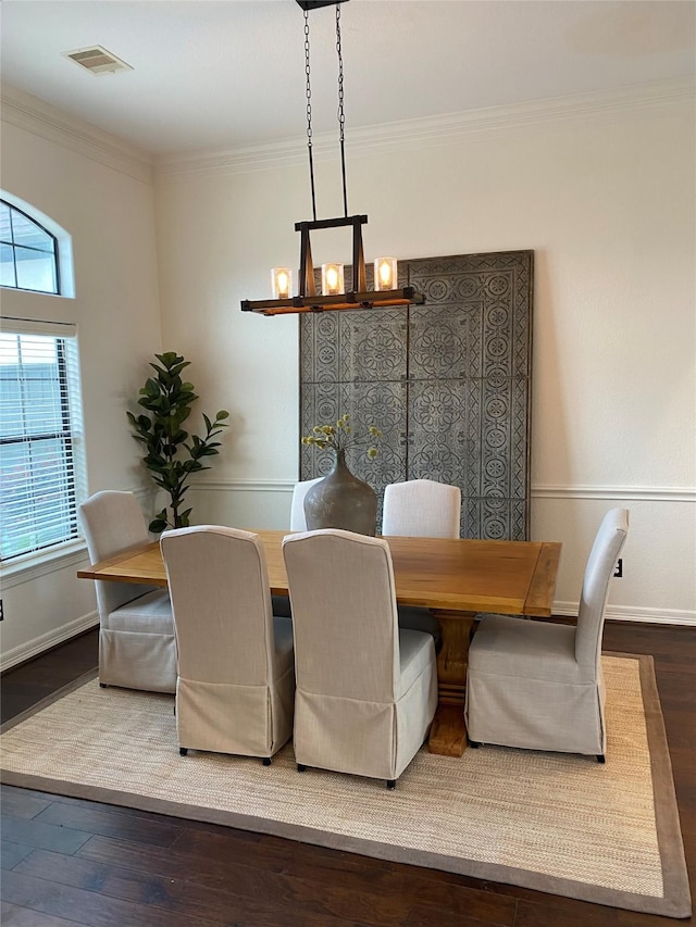 dining space with hardwood / wood-style flooring, ornamental molding, and an inviting chandelier