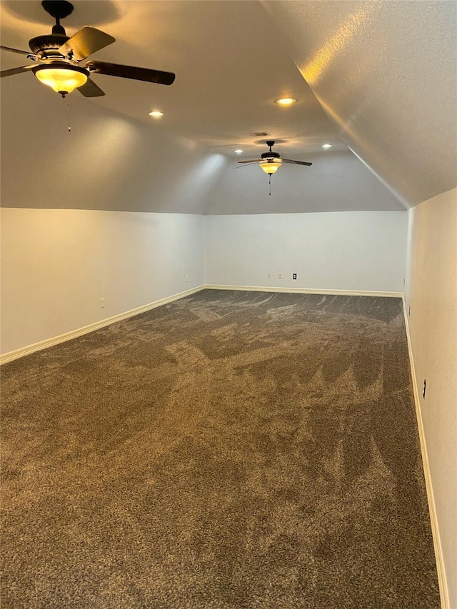 bonus room featuring ceiling fan, lofted ceiling, dark carpet, and a textured ceiling