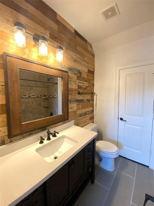 bathroom featuring tile patterned floors, toilet, vanity, and wood walls