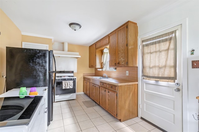 kitchen with sink, white gas stove, black refrigerator, and light tile patterned floors