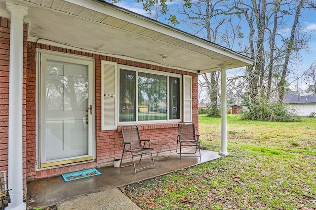 entrance to property featuring covered porch and a lawn