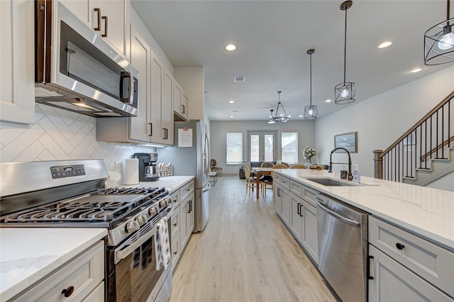 kitchen featuring hanging light fixtures, appliances with stainless steel finishes, sink, and light hardwood / wood-style floors