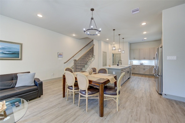 dining room with an inviting chandelier, sink, and light hardwood / wood-style floors