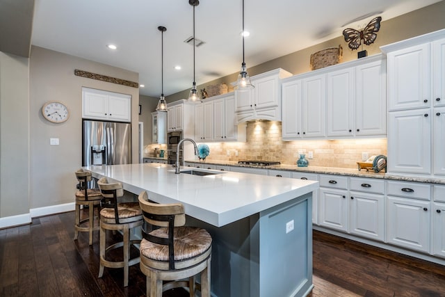 kitchen with stainless steel appliances, white cabinetry, a kitchen island with sink, and sink