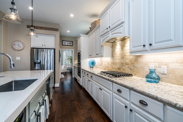 kitchen with light stone counters, sink, hanging light fixtures, and white cabinets