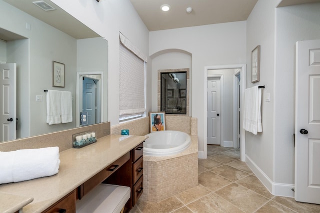 bathroom with vanity, a relaxing tiled tub, and tile patterned floors