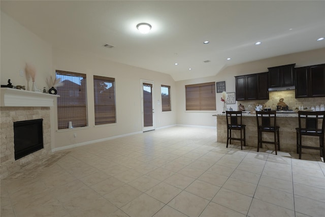 kitchen featuring vaulted ceiling, a kitchen island, a breakfast bar, decorative backsplash, and light tile patterned floors