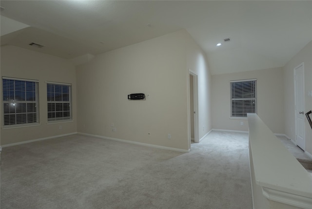 carpeted spare room with vaulted ceiling