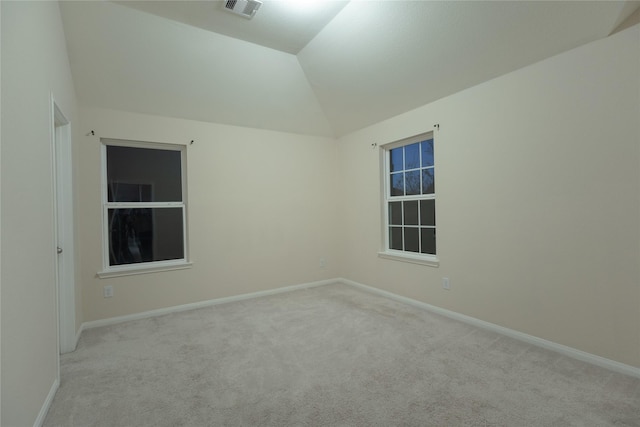 carpeted empty room with vaulted ceiling