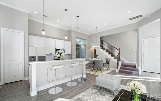 kitchen featuring pendant lighting, a breakfast bar area, built in refrigerator, white cabinets, and a kitchen island