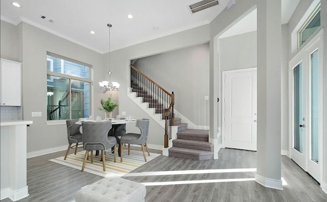 foyer entrance featuring ornamental molding, wood-type flooring, and a notable chandelier