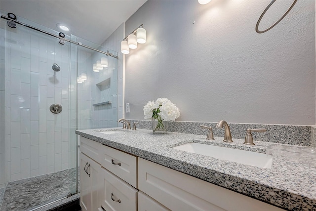 bathroom featuring a shower with shower door and vanity