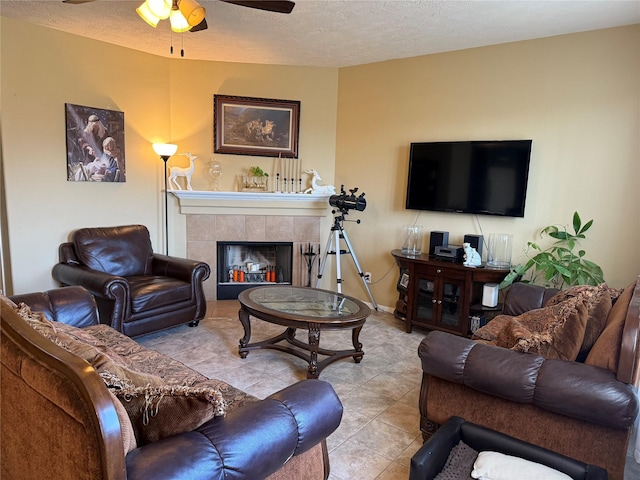 living room with light tile patterned flooring, ceiling fan, a fireplace, and a textured ceiling