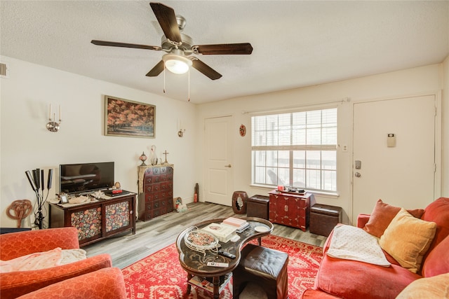 living room with a textured ceiling, visible vents, and wood finished floors