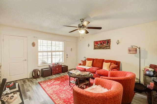 living room featuring ceiling fan, a textured ceiling, and wood finished floors