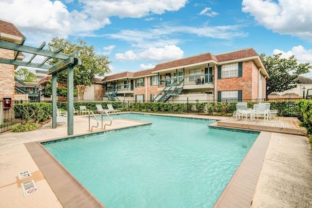 community pool with a patio area, fence, and a pergola