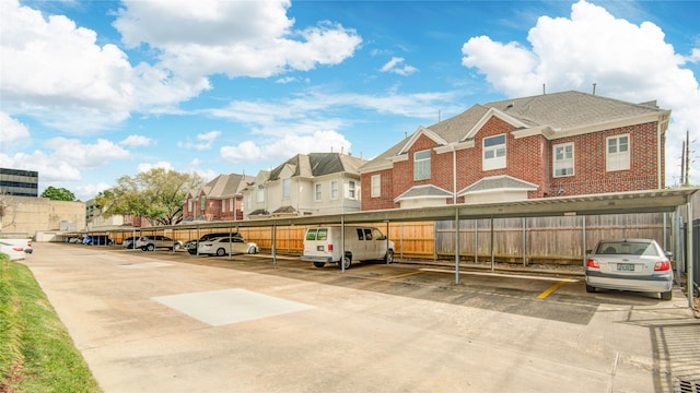 covered parking lot featuring a residential view and fence