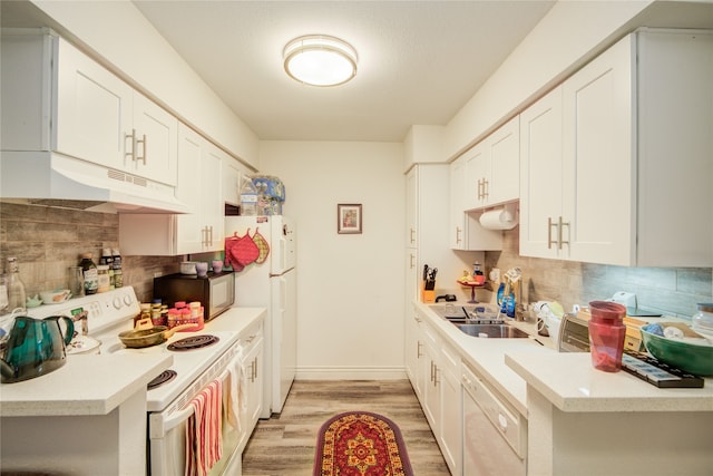 kitchen with under cabinet range hood, white appliances, light wood-style floors, light countertops, and backsplash