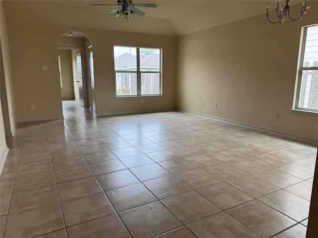 tiled empty room featuring ceiling fan with notable chandelier