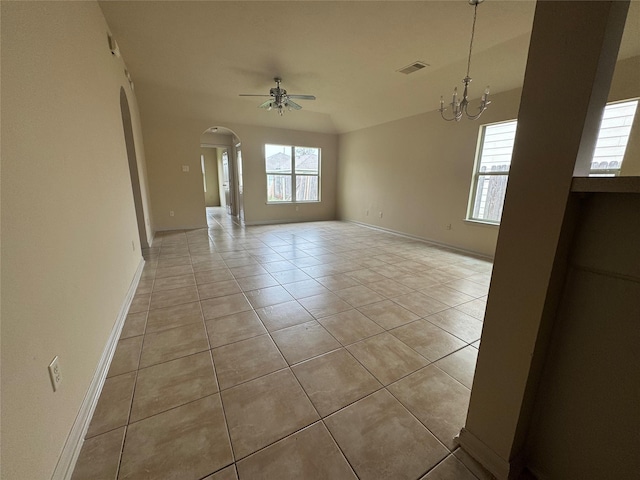 tiled spare room featuring ceiling fan with notable chandelier