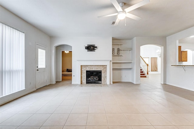 unfurnished living room featuring a tiled fireplace, light tile patterned floors, and ceiling fan