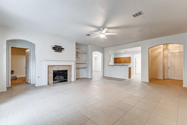 unfurnished living room featuring light tile patterned flooring, a fireplace, and ceiling fan