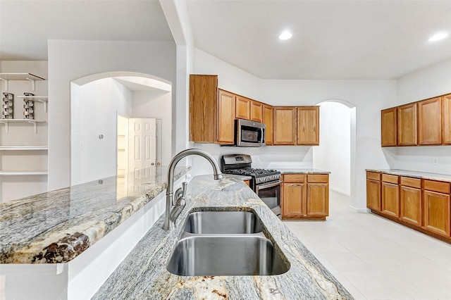 kitchen with stainless steel appliances, light stone countertops, and sink