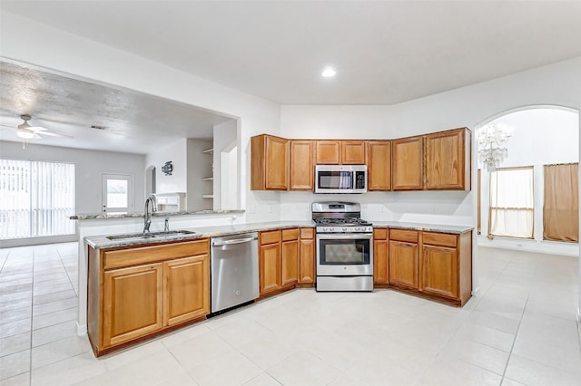 kitchen featuring sink, light stone counters, kitchen peninsula, ceiling fan, and stainless steel appliances