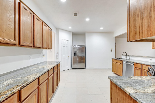 kitchen with light stone counters, sink, light tile patterned floors, and stainless steel appliances